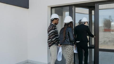 A group of diverse clients with a realtor at a new construction site entrance.