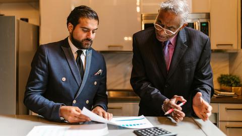 Two businessmen engaged in a focused discussion over financial documents in a modern office setting.