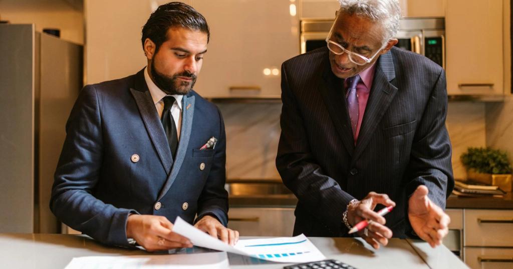 Two businessmen engaged in a focused discussion over financial documents in a modern office setting.