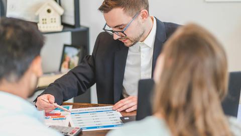 A real estate agent explains mortgage options to clients in an office setting.