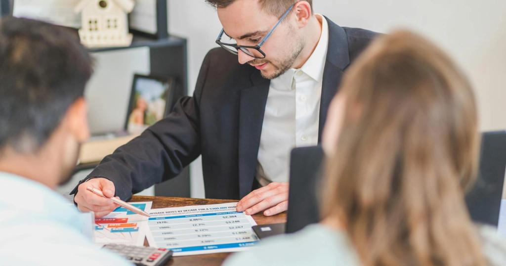 A real estate agent explains mortgage options to clients in an office setting.