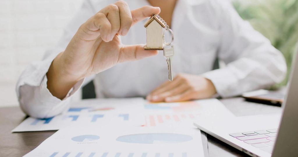 Real estate professional presenting a house model with keys, symbolizing property investment and ownership.