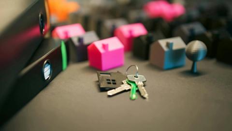 Miniature model houses and keys on a desk, symbolizing real estate and property investment.
