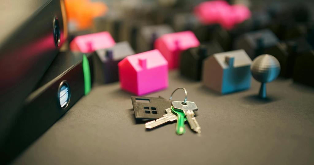 Miniature model houses and keys on a desk, symbolizing real estate and property investment.