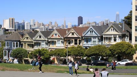 a group of people sitting on the grass in front of a row of houses