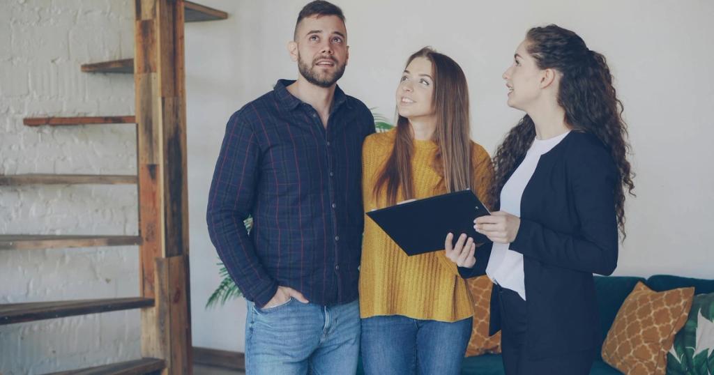 Young couple exploring a new home with their real estate agent, discussing options and features.
