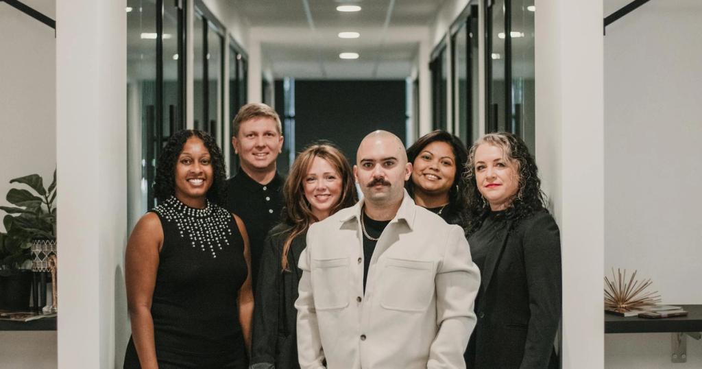 Diverse team of professionals posing in a modern office hallway in Greenville, SC.
