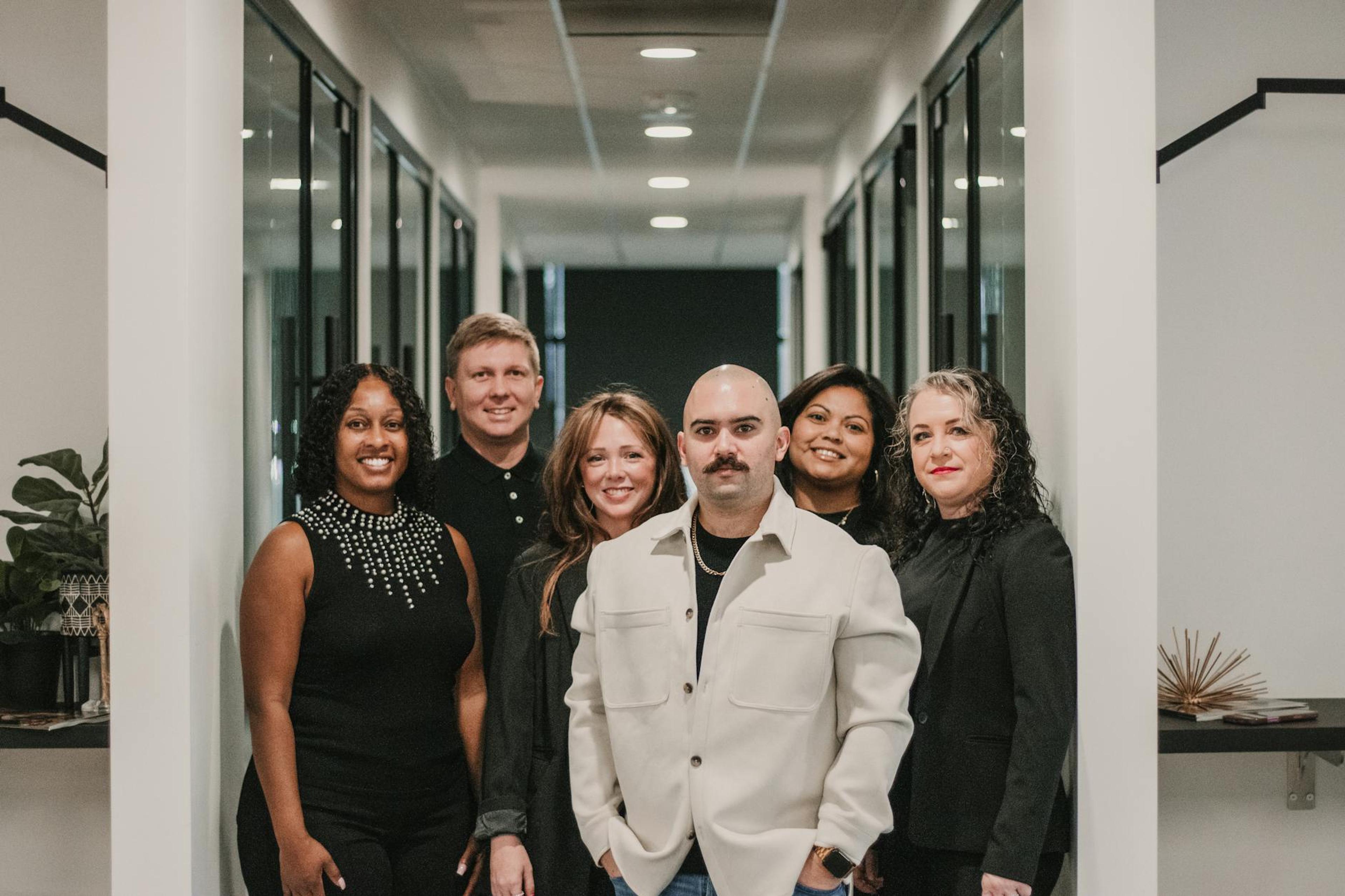 Diverse team of professionals posing in a modern office hallway in Greenville, SC.