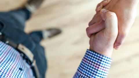 Close-up of a handshake between two people inside an office, symbolizing trust and cooperation.