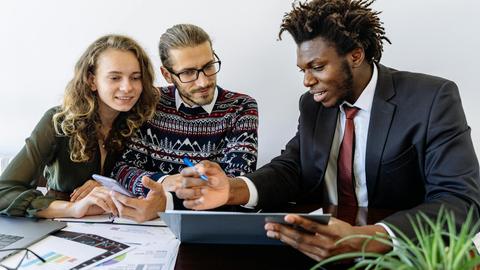 Three professionals engaging in a collaborative business meeting in a modern office environment.