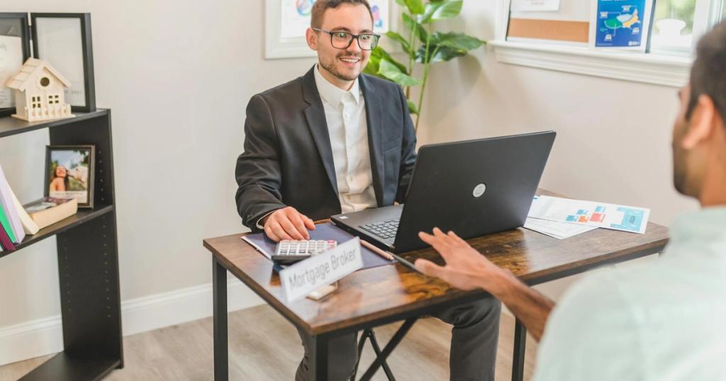 Mortgage broker in an office meeting with a client, utilizing a laptop.