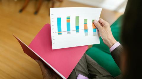 Close-up of a person analyzing a printed business report featuring a colorful bar graph.