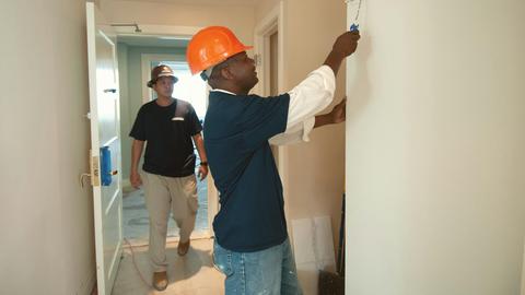Two construction workers painting and renovating an interior. Focus on teamwork and home improvement.