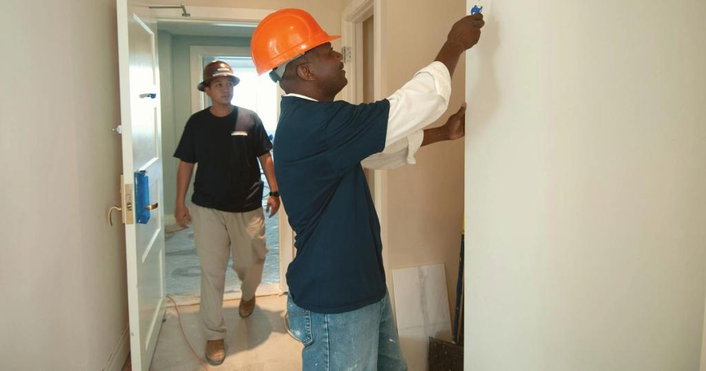 Two construction workers painting and renovating an interior. Focus on teamwork and home improvement.