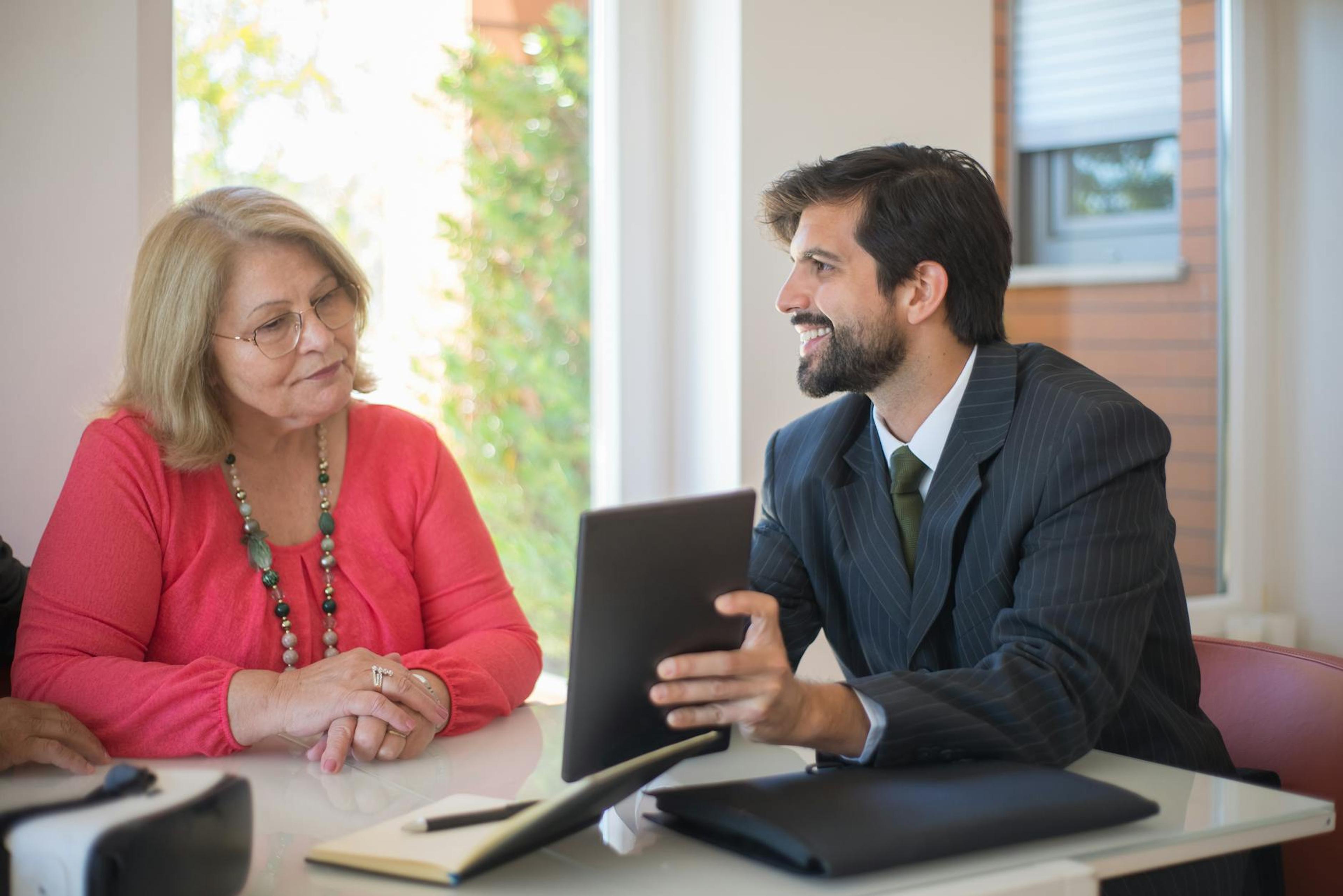 Elderly woman consulting with a realtor about a property deal in a cozy indoor setting.