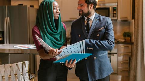 Smiling colleagues in a modern office discussing documents and business opportunities.