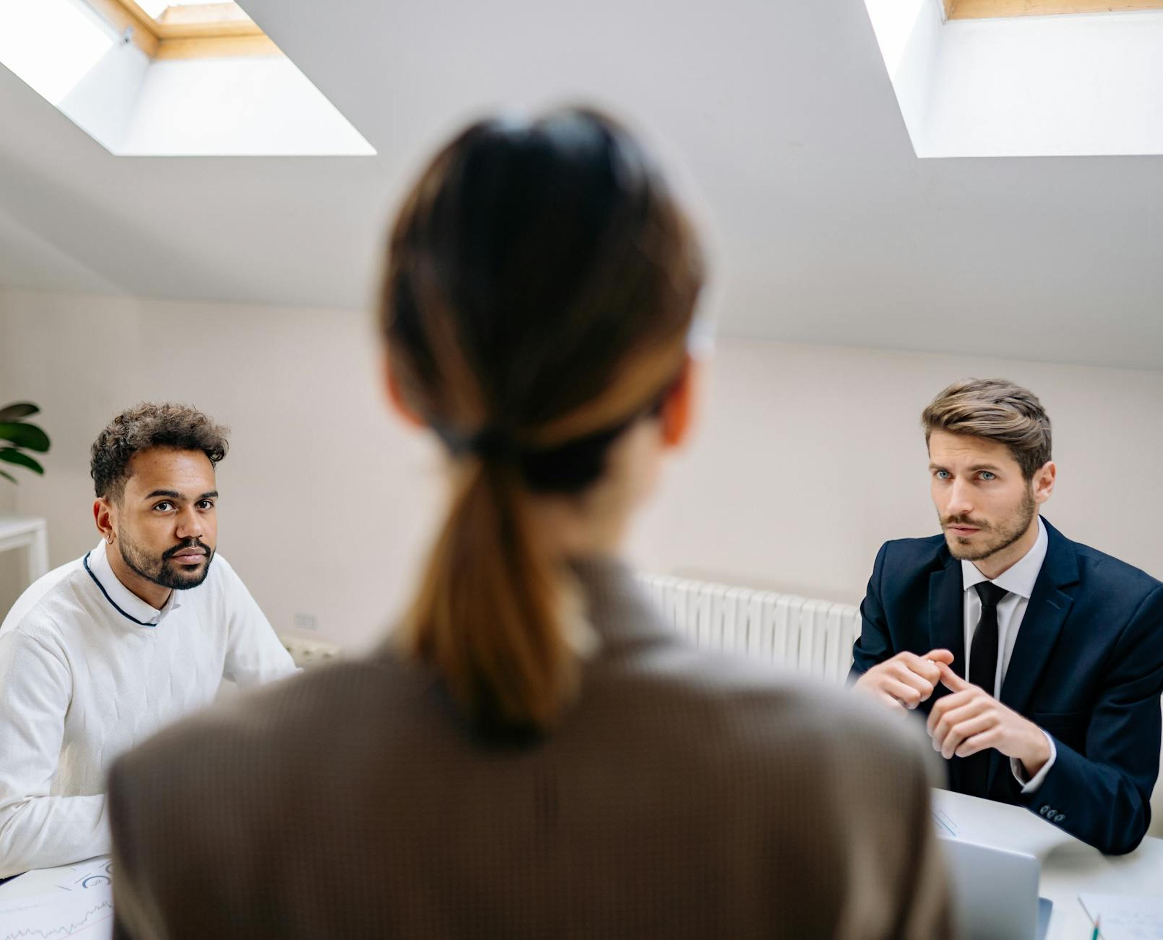 A professional business meeting involving three adults in a modern office setting.