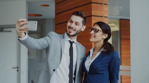 Man and woman taking a selfie in office building.