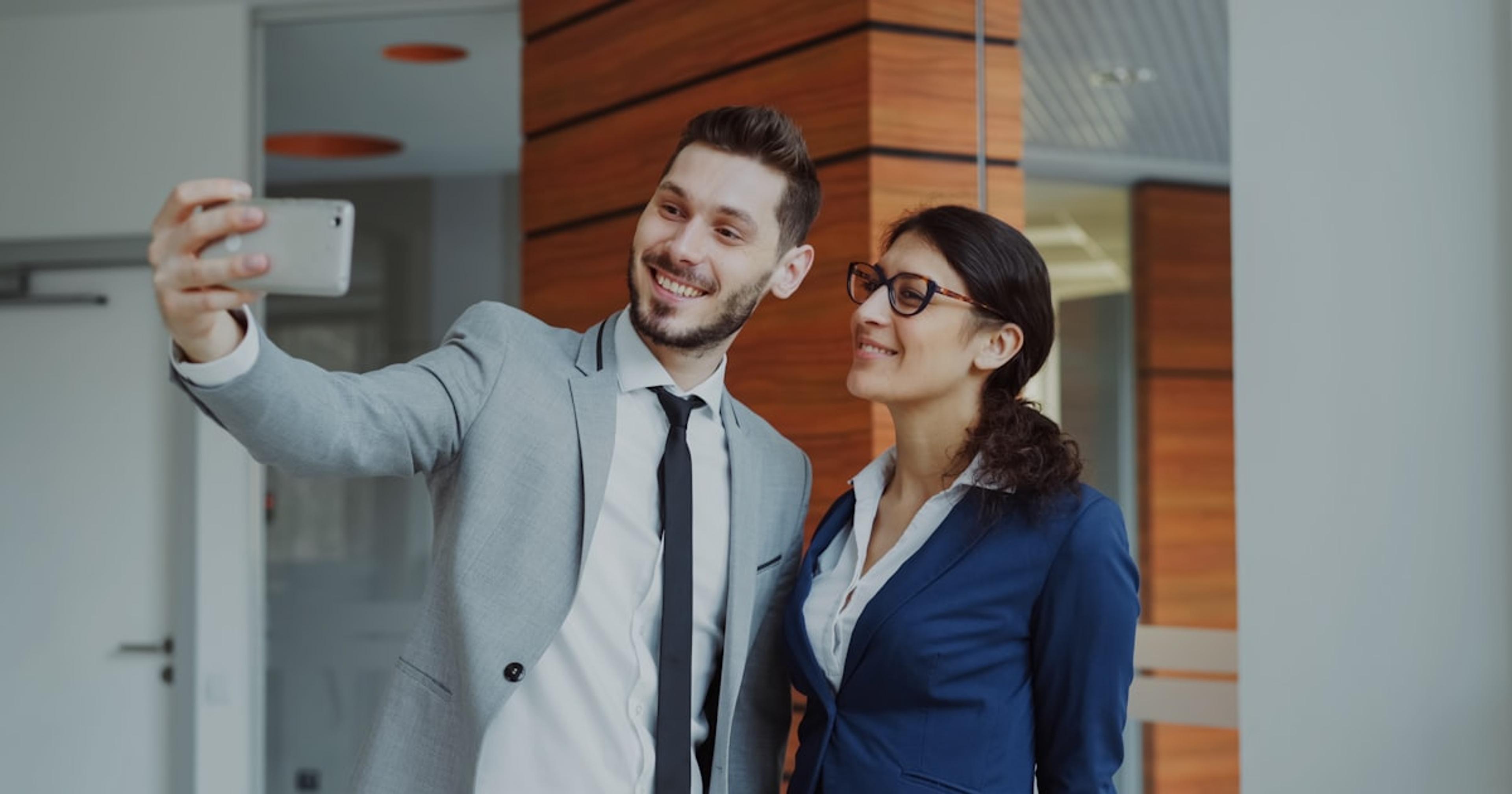 Man and woman taking a selfie in office building.