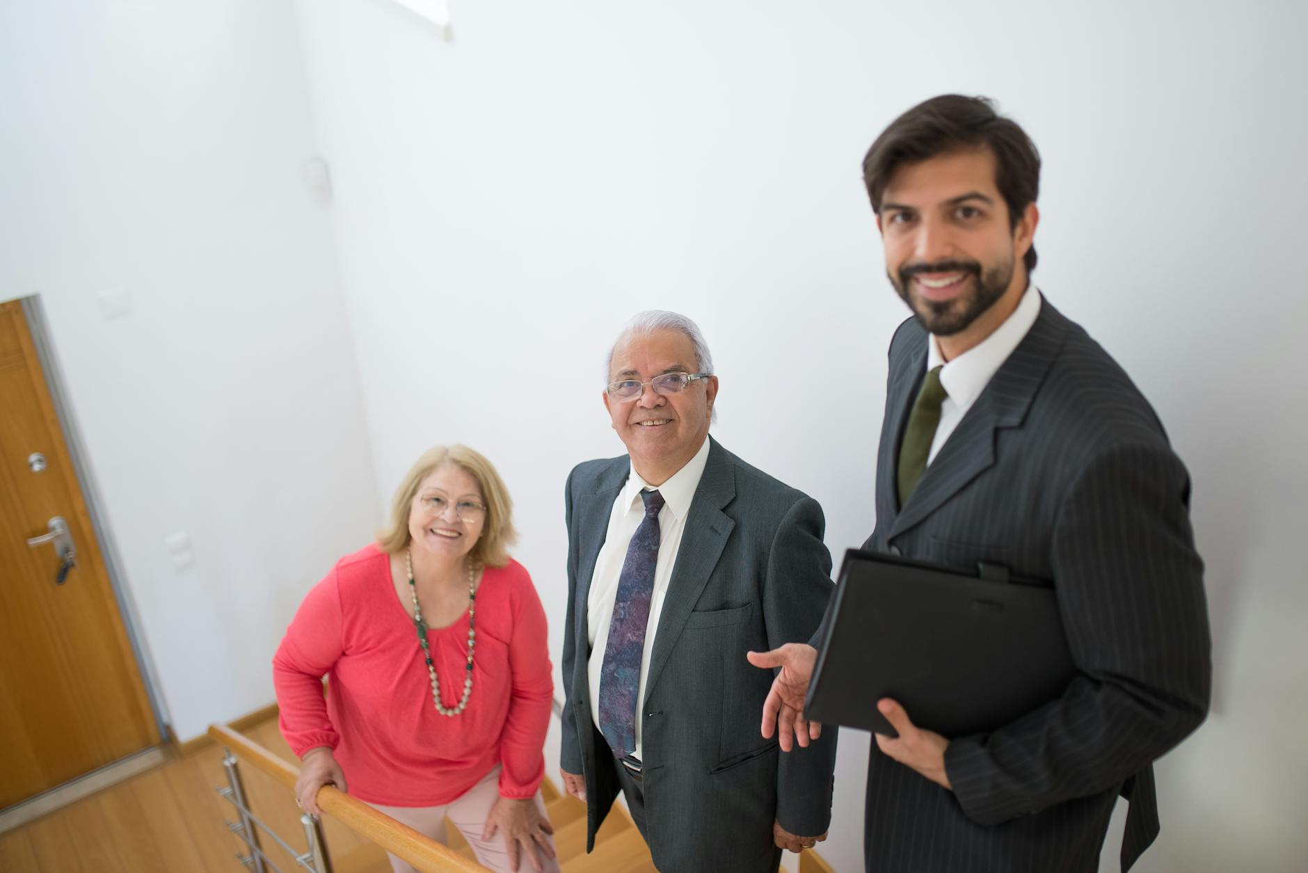 Realtor assists senior couple in a modern home setting. Ideal for real estate themes.