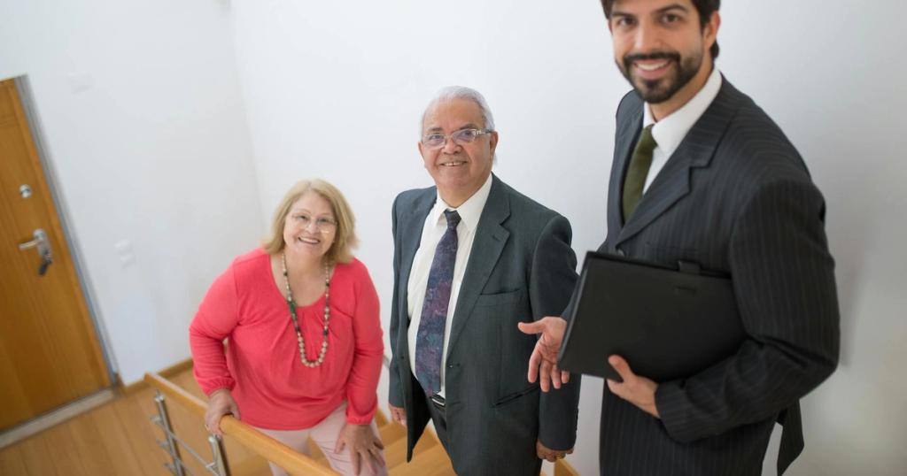 Realtor assists senior couple in a modern home setting. Ideal for real estate themes.