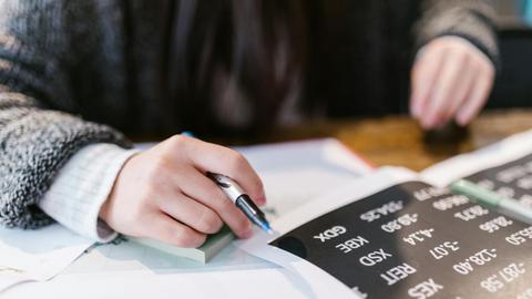 Close-up of a woman reviewing financial documents with focus on numbers and calculations.