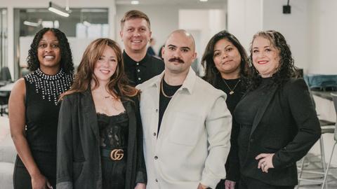 Diverse real estate professionals posing confidently in a modern office environment.