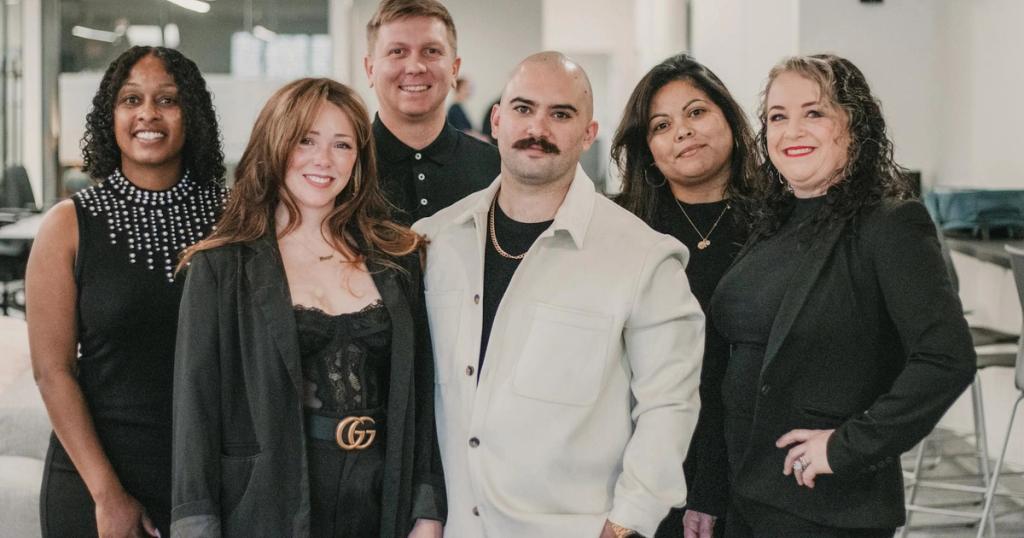 Diverse real estate professionals posing confidently in a modern office environment.