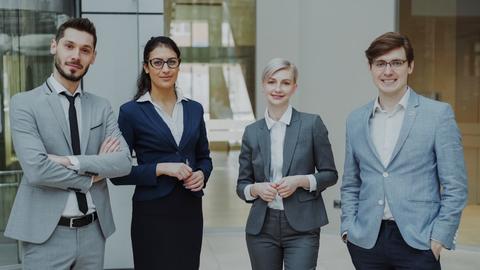 Four professionals in business attire stand together.