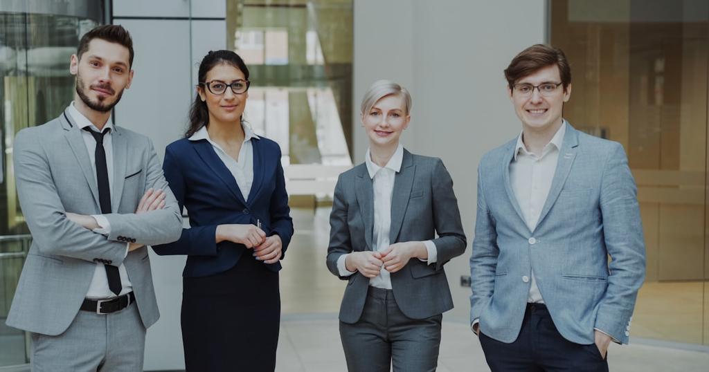 Four professionals in business attire stand together.
