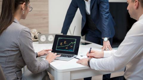 Professional team analyzing stock market trends on a laptop during a meeting.