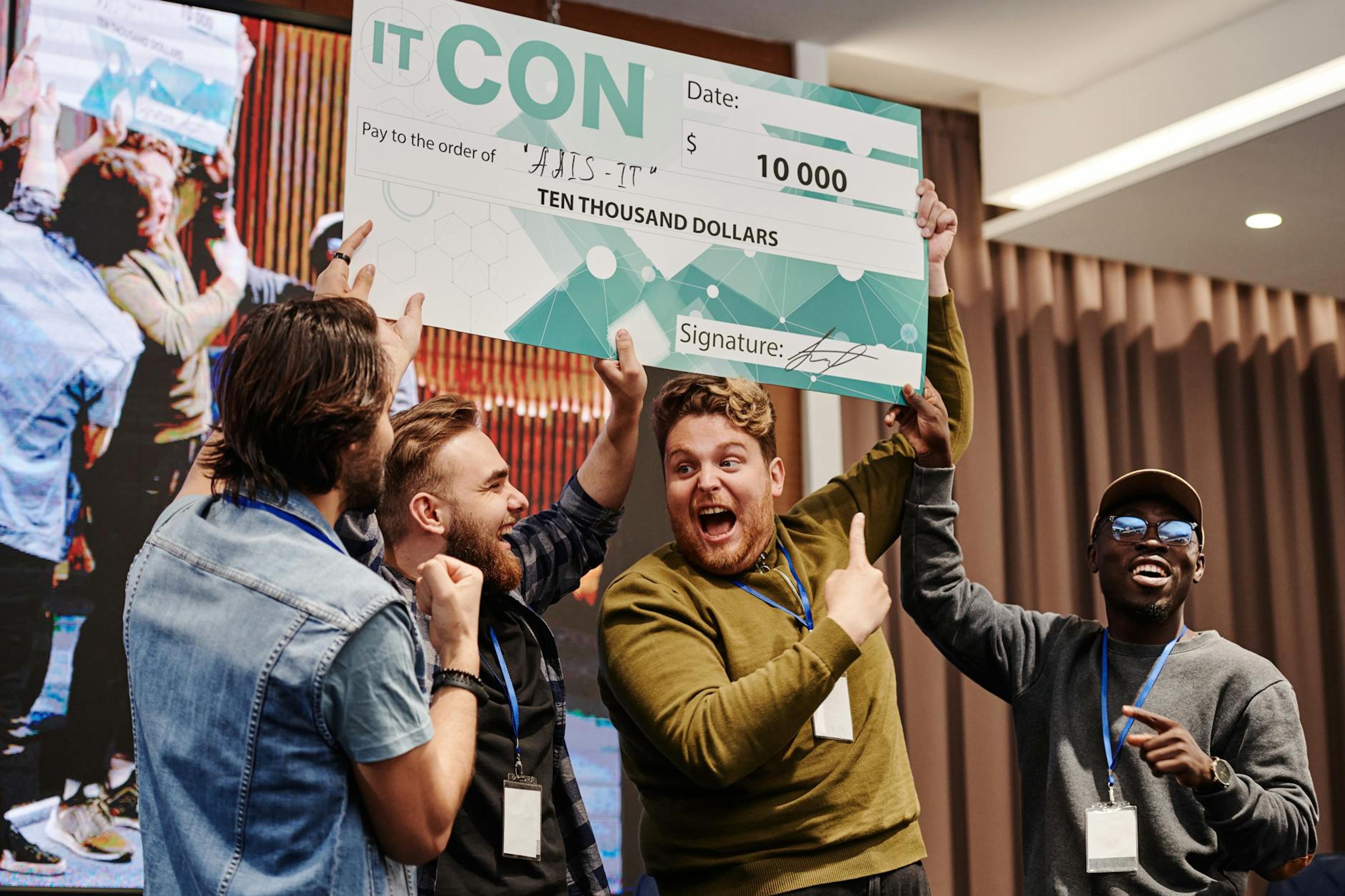 Excited business team celebrates winning a ten thousand dollar prize at a tech conference.