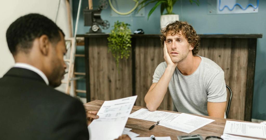 Man in office, appearing stressed during paperwork discussion, sitting opposite professional.