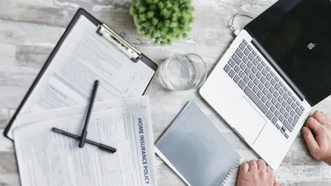 Top view of home insurance forms, laptop, and documents on a desk, conveying a professional office setting.