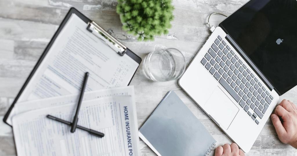 Top view of home insurance forms, laptop, and documents on a desk, conveying a professional office setting.
