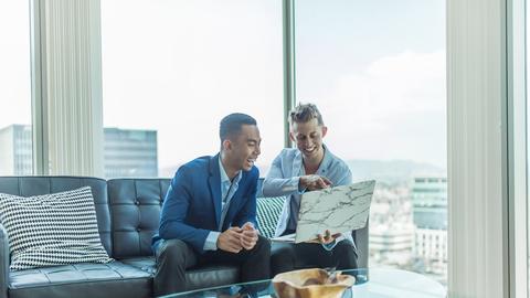 two men in suit sitting on sofa