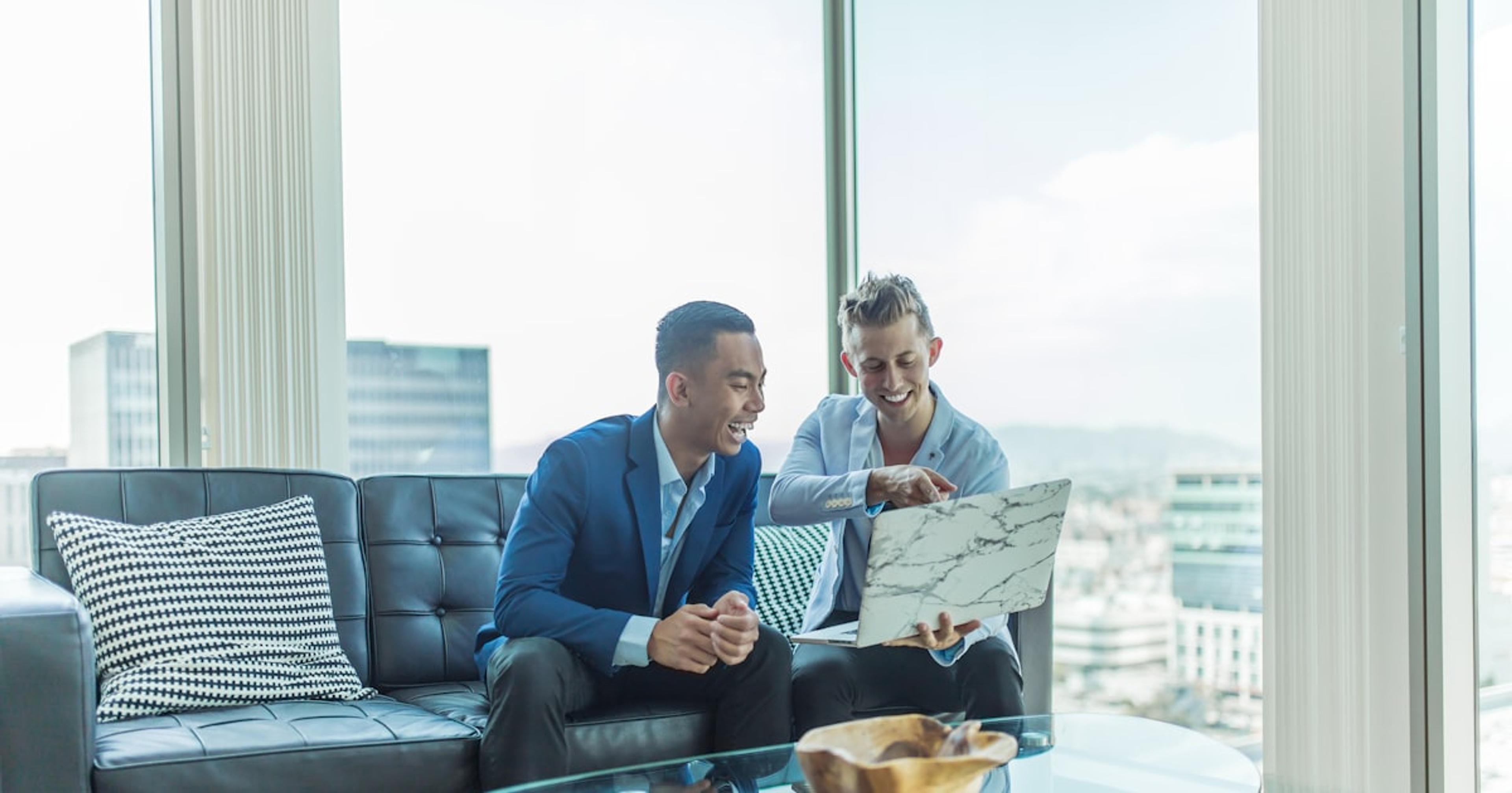 two men in suit sitting on sofa