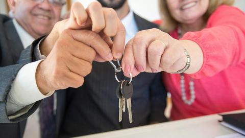 Business colleagues celebrating a successful deal with a handshake and keys exchange.