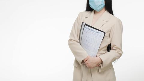 Professional woman wearing face mask holding insurance document, demonstrating safety and business.