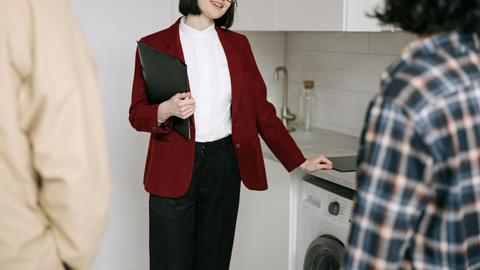 Real estate agent with clients in a modern kitchen during apartment viewing. Professional and engaging.