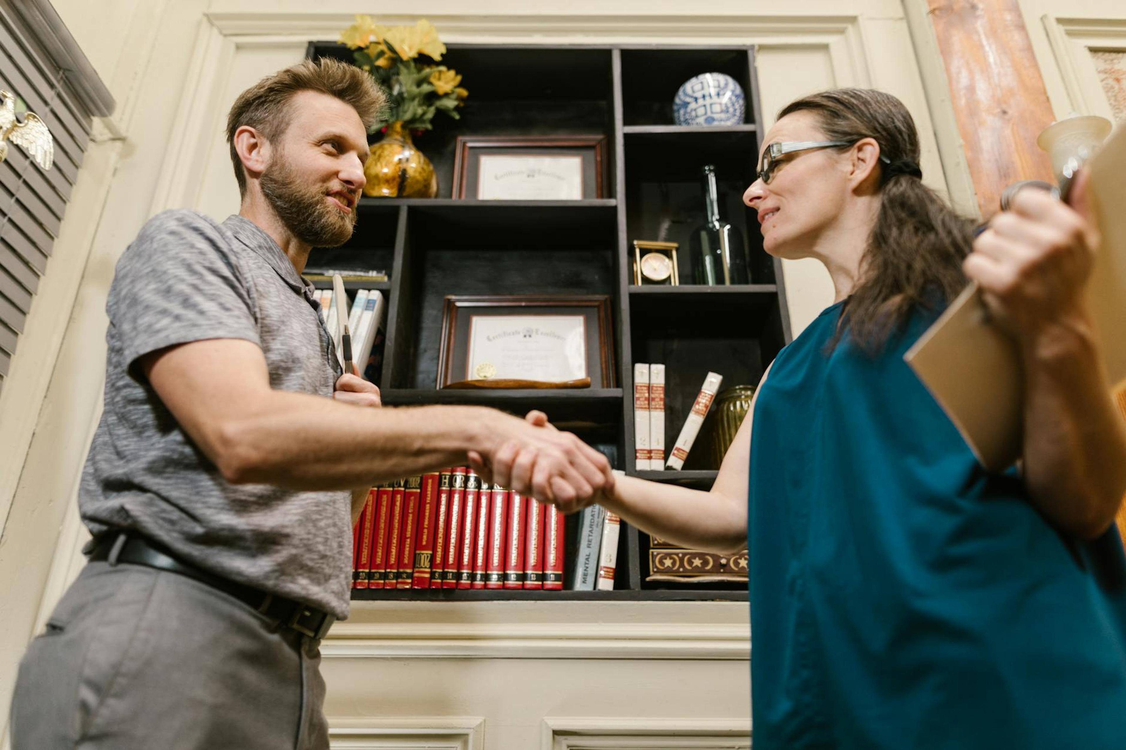 Professional handshake between a man and a woman in an office environment, symbolizing partnership.