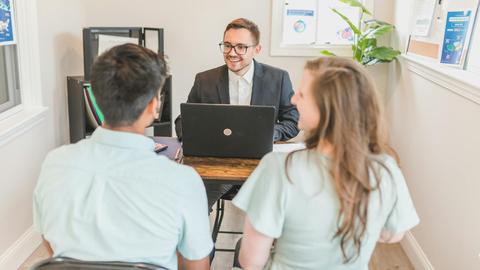 Couple consulting with a real estate agent about buying a new home in a bright and modern office.