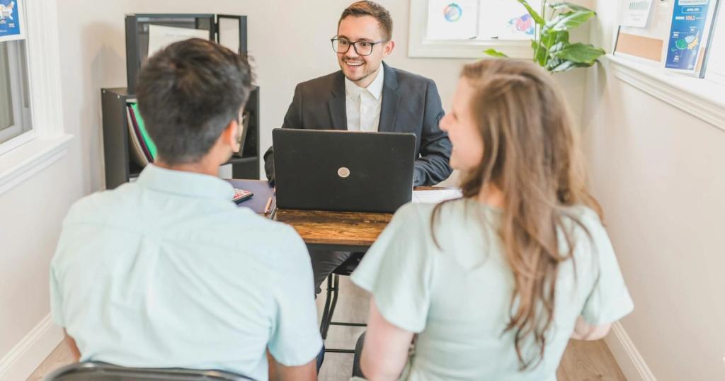 Couple consulting with a real estate agent about buying a new home in a bright and modern office.