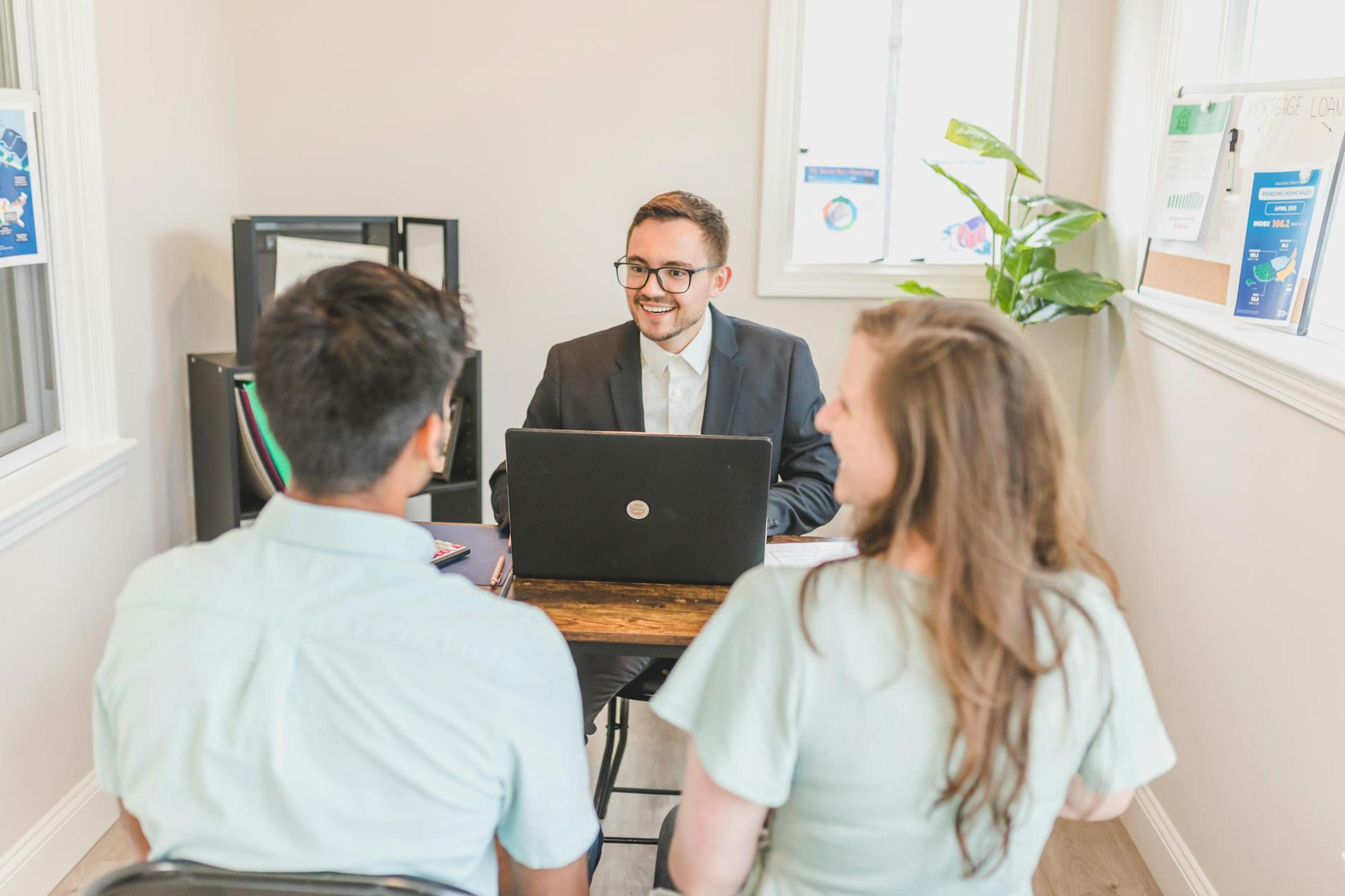 Couple consulting with a real estate agent about buying a new home in a bright and modern office.