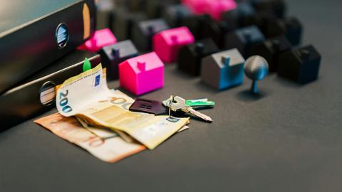 Miniature houses, euro bills, and a house key symbolize real estate investment and property transactions.