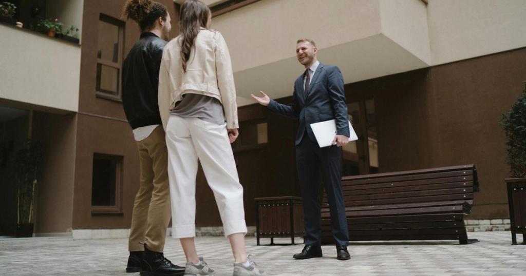 A realtor converses with a couple in a modern apartment courtyard.