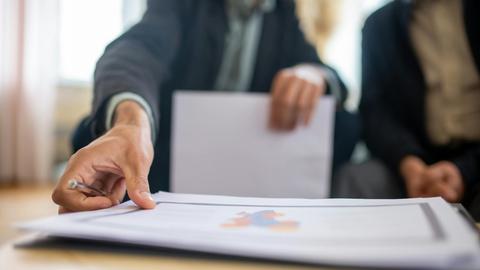 Close-up of a businessman reviewing important documents at a desk in an office setting.