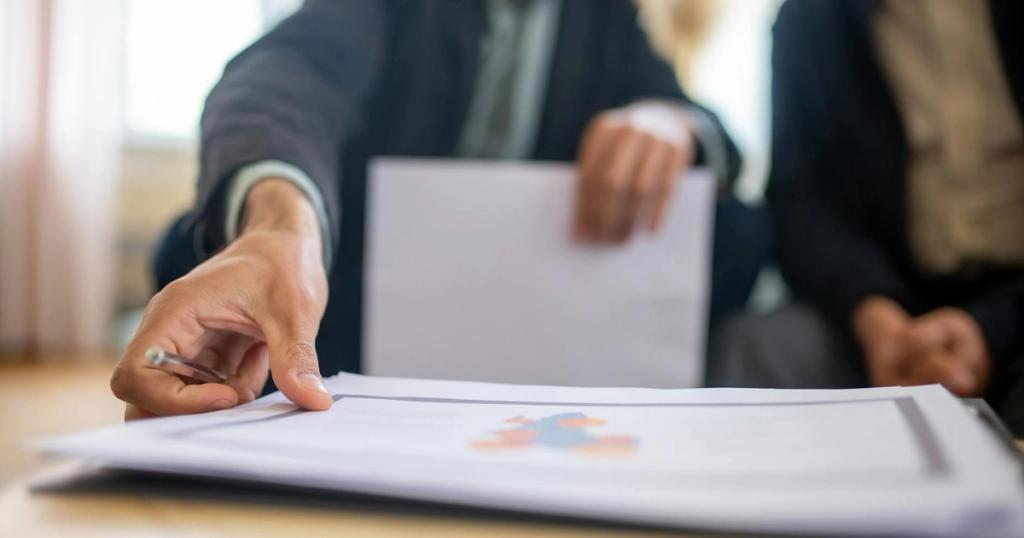 Close-up of a businessman reviewing important documents at a desk in an office setting.