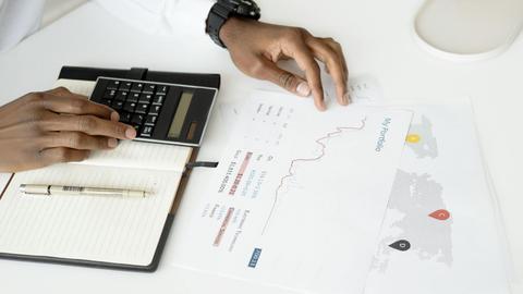 Overhead view of a person analyzing financial documents using a calculator for investment planning.