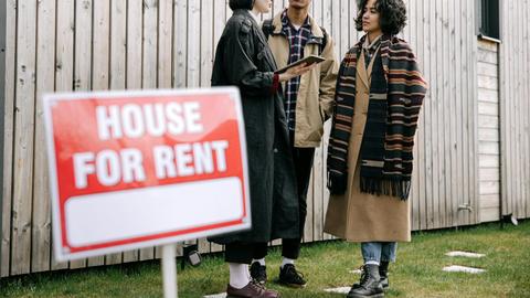 An interracial couple meets with a real estate agent to inquire about a house for rent.